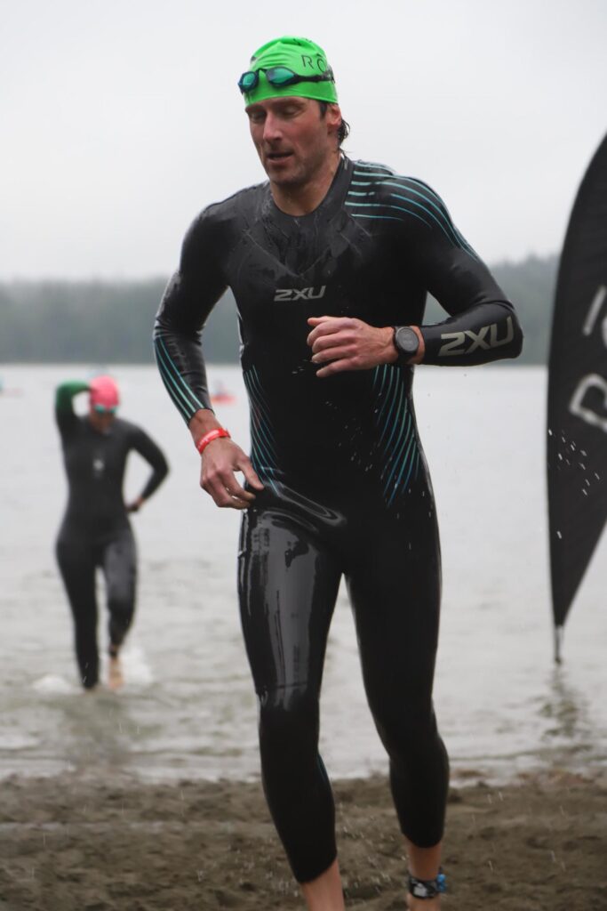 Jay running out of the water in a wetsuit after the swim